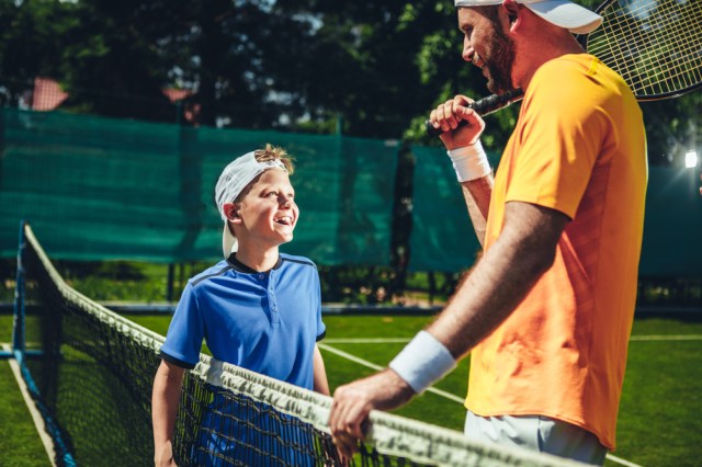Laughing child looking at glad trainer while speaking with him.
