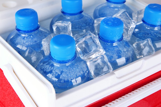 Bottles of water and ice cubes in traveling refrigerator, close up