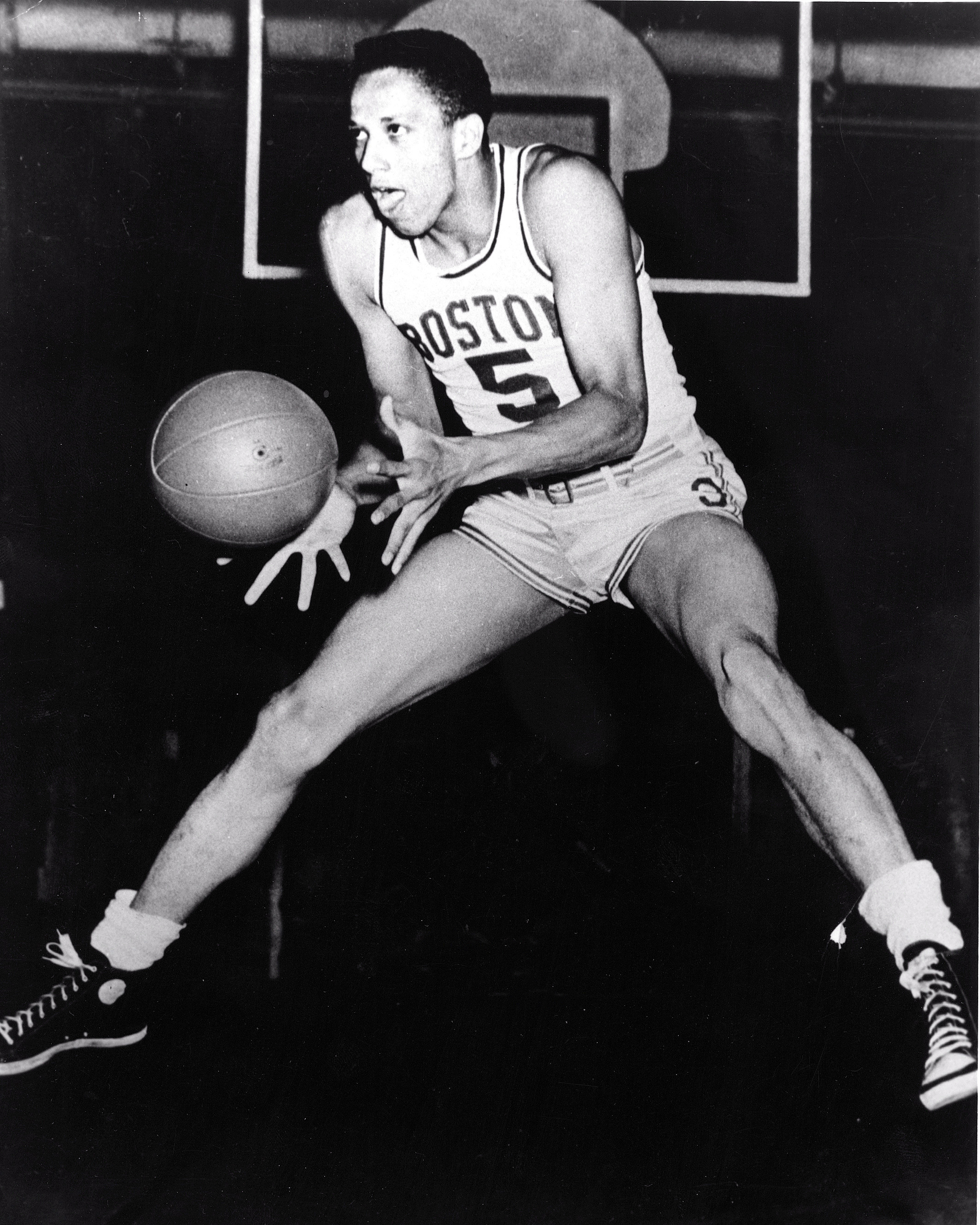 Chuck Cooper wearing his uniform jumping in the air and catching a basketball
