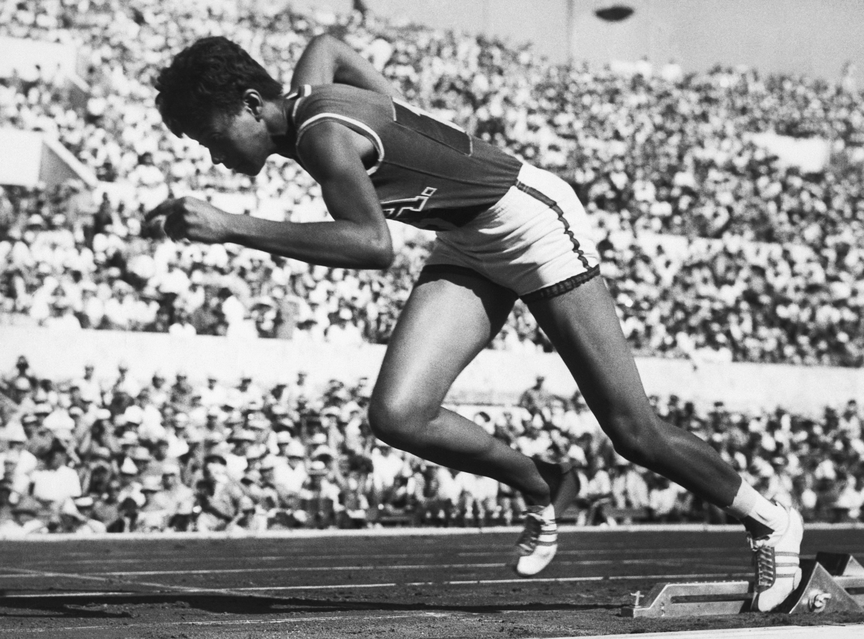 Wilma Rudolph springing from the starting block at the beginning of the race.