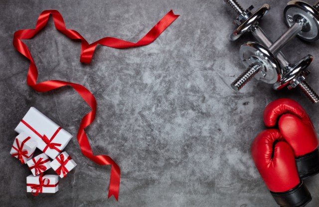 Dumbbells, boxing gloves, gift boxes on grey background