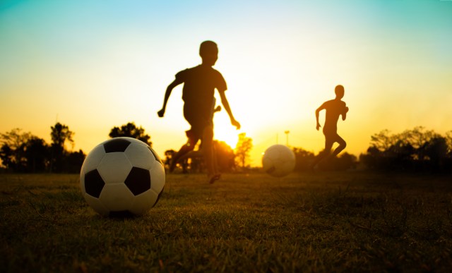 Silhouette action sport outdoors of a group of kids having fun playing soccer