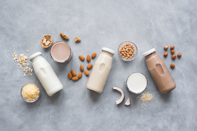 Various vegan plant based milk and ingredients, top view, copy space. Dairy free milk substitute drink, healthy eating.