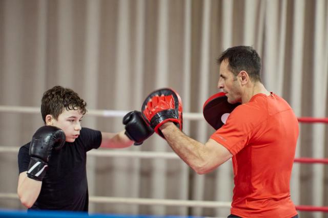 Young kickbox fighter hitting mitts with his coach