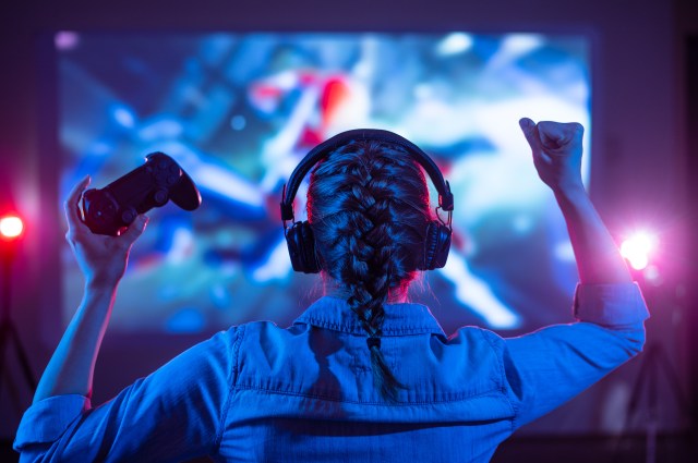 Girl in headphones plays a video game on the big TV screen