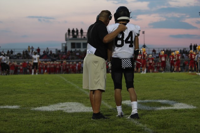 A high school football coach talks to a player