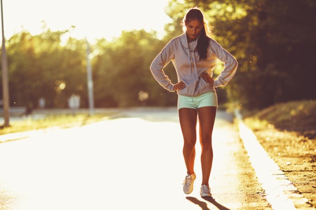 Tired female runner taking a break after jogging .
