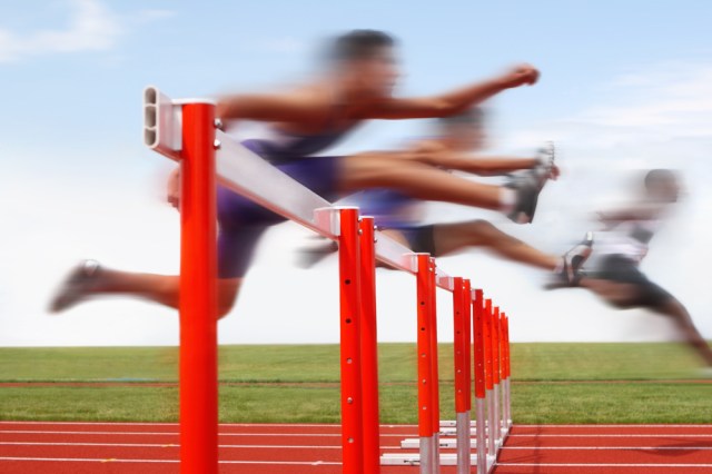 Hurdle race, men jumping over hurdles in a track and field race