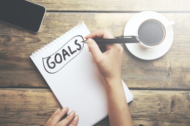 Goals memo written on a notebook with woman hand pen