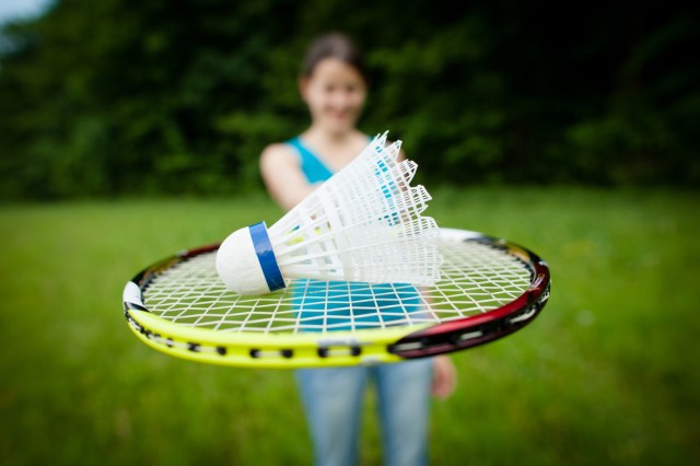 Pretty, young woman playing badminton in a city park